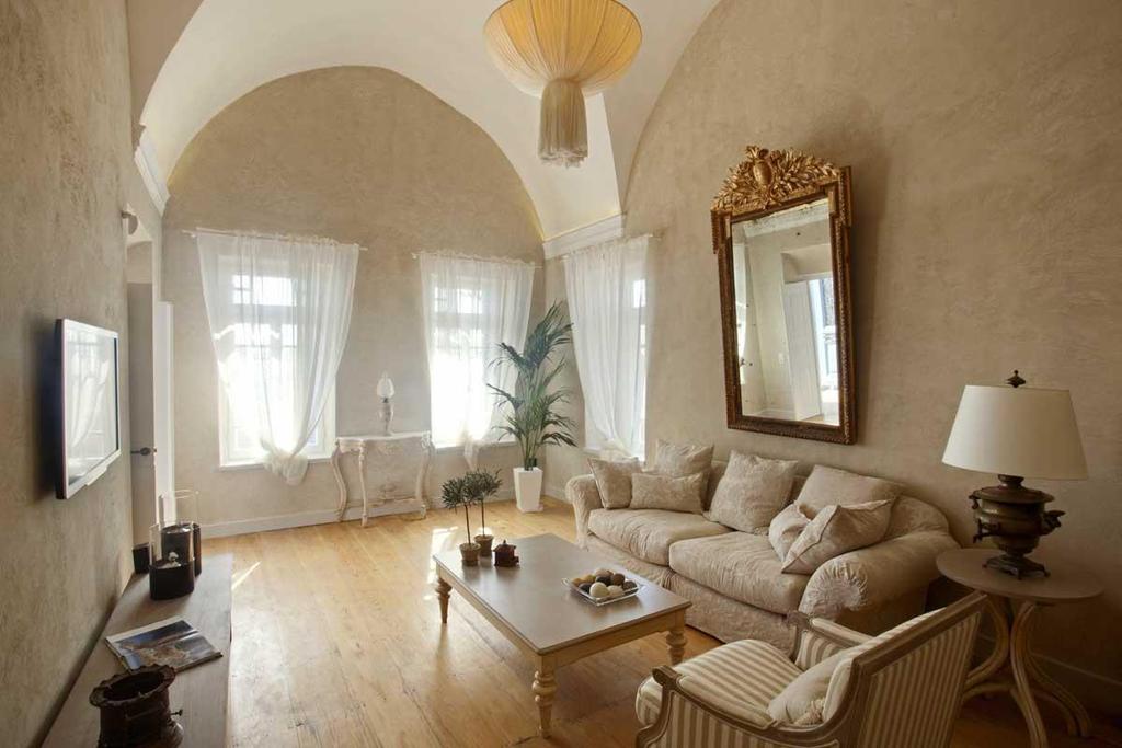 The Living Room The living room is an equally gracious space with high cross-vaulted ceilings, beige textured walls, the authentic wooden floors and the large sculptured Venetian mirror.