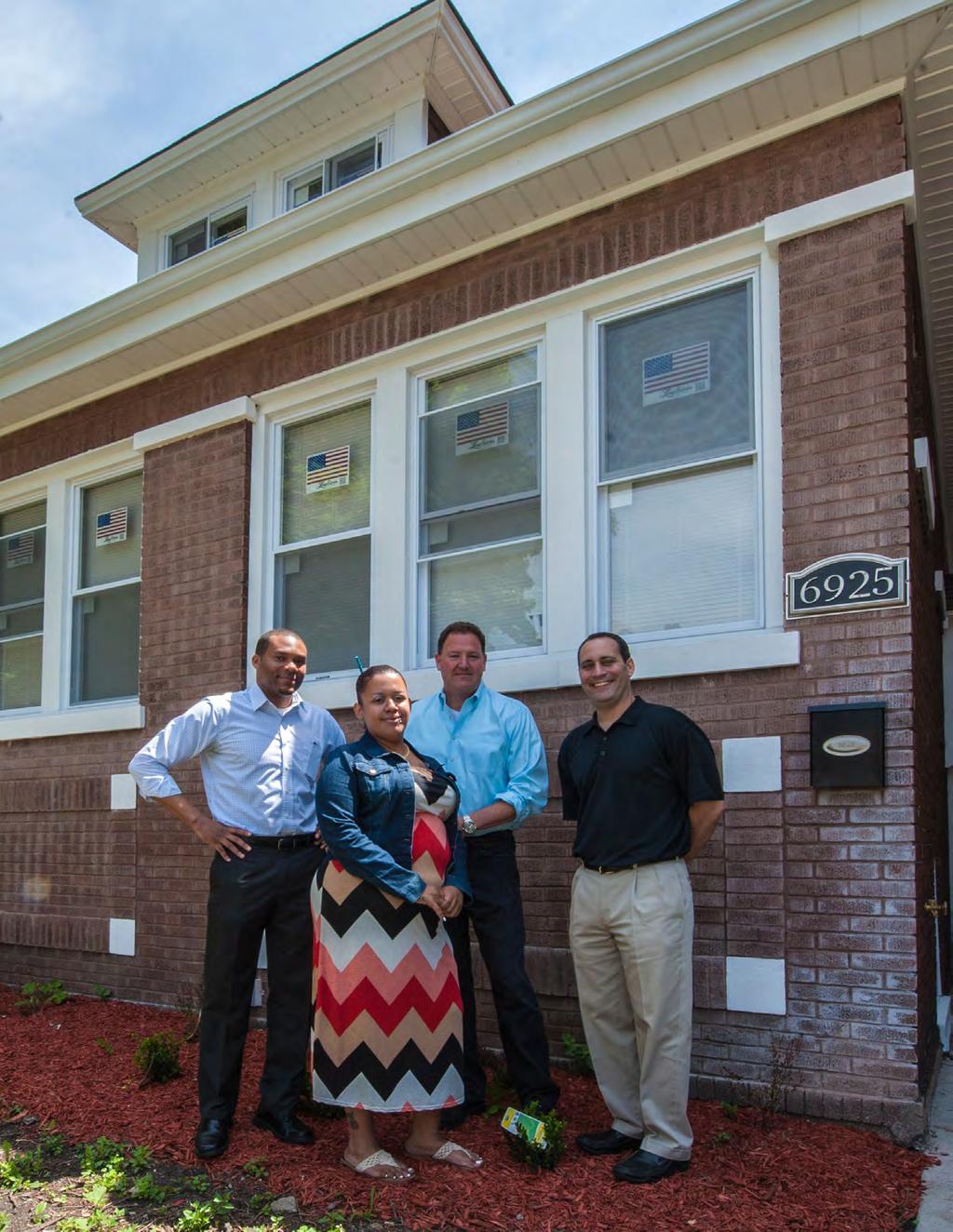 A RESTORED HOME A tenant stands in front of her new home, with (left to right) Andre Collins, who acquired the home for the Collaborative; Scott Allbright, who bought the home from the Collaborative