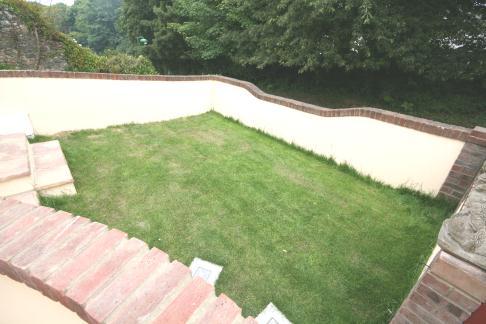 Outside: Front/Side : The property is approached up steps and on to an area laid to lawn, up a further two steps on to a lovely terraced area