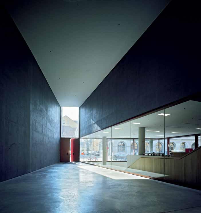 A view of the southern entrance shows the minimalist material concept of the east wing. The surfaces here are pared down to bare floors and painted concrete.