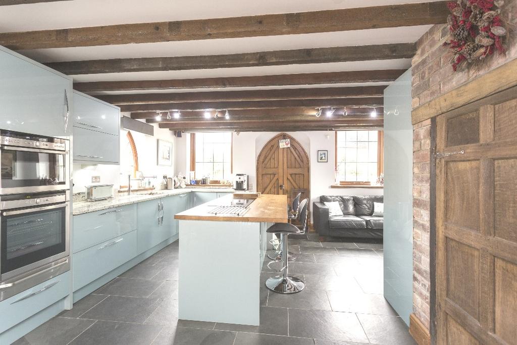 The kitchen has slate tiled flooring, exposed beams, exposed brickwork, windows to three sides, arched double