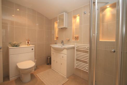 En Suite Shower room 7 7 x 6 1 Fitted with a white 3 piece suite comprising basin set in vanity unit with cupboards below, fully tiled corner shower