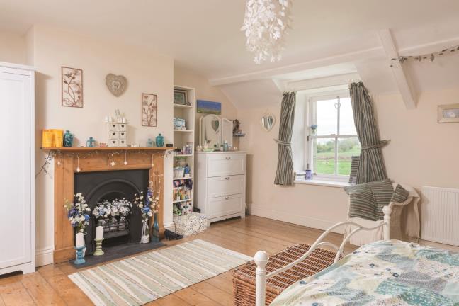 wood mantle and tiled surrounds. The beamed ceiling is an attractive feature of the room. insert and open grate, stripped wood floor boarding, single panelled radiator and built-in store cupboard.