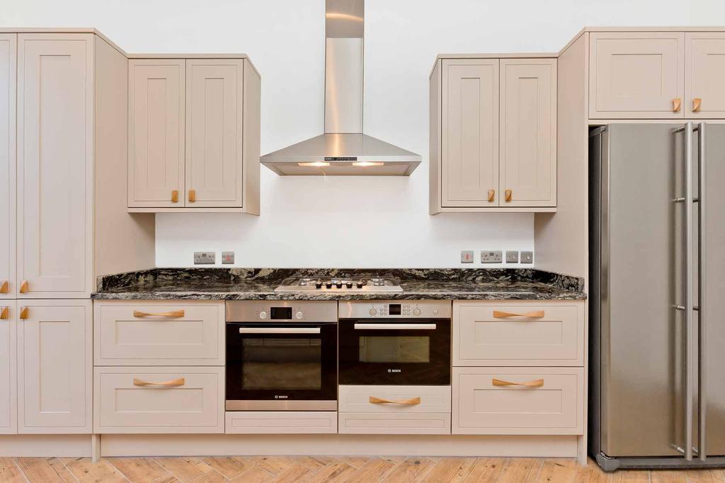 A Bosch integrated double oven, accompanied by a five-ring burner and a statement chimney hood, adds an impressive focal