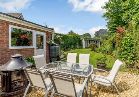 There is a separate sitting room with double sided log burning stove, a downstairs cloakroom, and patio doors lead from the dining area to the well-maintained, mature rear garden.