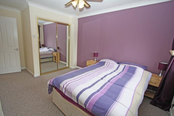 This room has carpet underfoot, light decor to walls and ceilings, central heating, a built in double mirror door wardrobe with shelving and hanging space, and finished with ceiling lighting/fan,