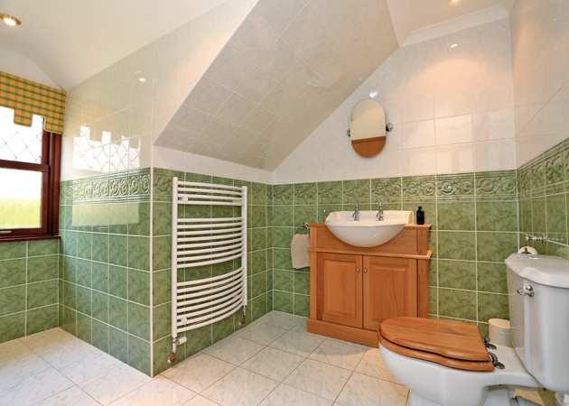 The walls and floor are fully tiled and there is a radiator and recessed ceiling lighting. A frosted glazed window overlooks the rear of the property. Heated towel rail and wall mounted mirror.