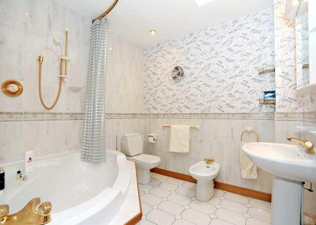 BATHROOM A spacious family bathroom comprising a four piece suite of corner bath with shower over,