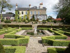 GARDENS AND GROUNDS The property is approached through imposing brick gate piers and the lengthy drive, with lawn either side studded with clipped yews, sweeps around to the front door of the house.