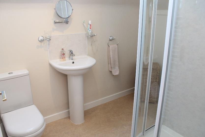 EN SUITE SHOWER ROOM : Freshly presented the en suite shower room has been fitted with a modern two piece white suite with a separate shower cubicle, finished with aqua panelling and fitted with a