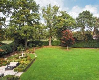 There is a large area of well maintained lawn dotted and surrounded by colourful flower beds, all enclosed by a variety of mature hedging, shrubs and trees.