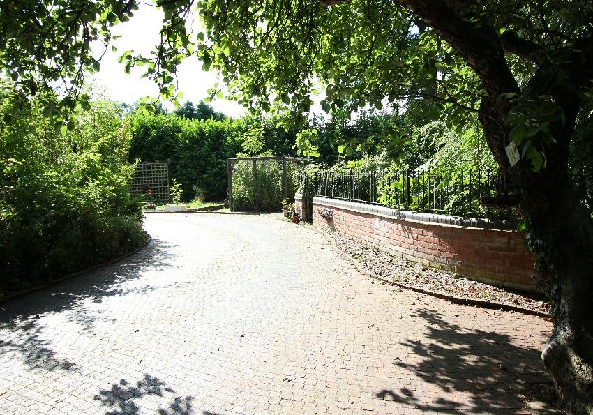 Double metal gates with brick pillars give access to a winding pavior driveway bounded by dwarf brick walling and shrubberies which are all filled with specimen plants and shrubs which with some care