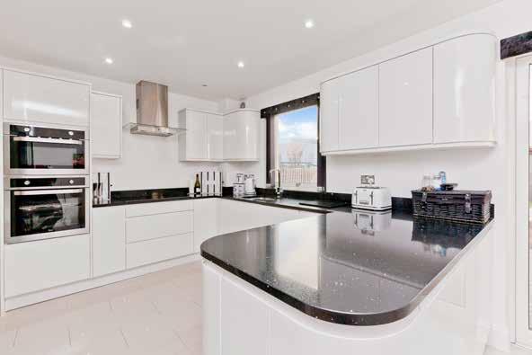 Boasting an ultra-modern monochrome style, the state-of-the-art kitchen is fitted with a wealth of glossy flat-panel cabinets with curved edges, and gleaming granite worktops.