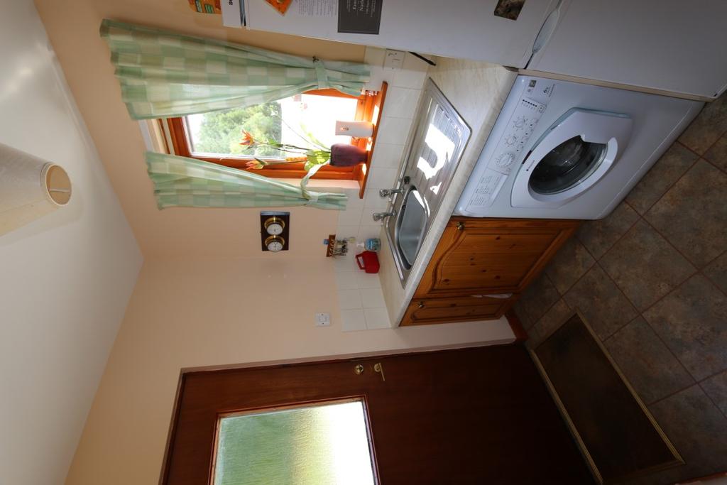 There is a cooker with extractor hood and decorative tiling above. A further doorway leads into the Utility Room measuring 2.