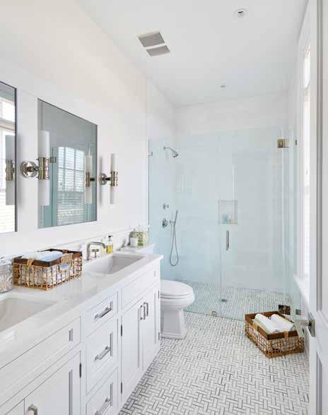 bathroom with dual vanities and a glass encased shower.