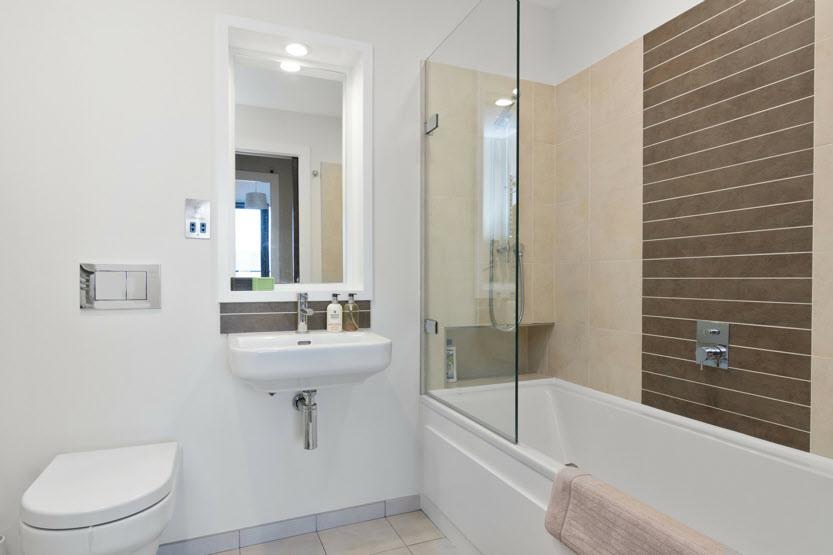 BATHROOM: Contemporary white suite comprising, panel bath with overhead shower,