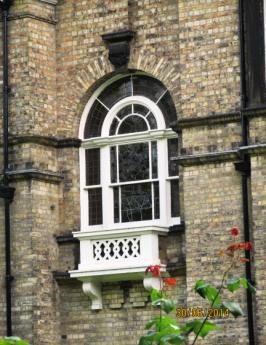 The tower has a large round-headed stair-window with arched centre light and radiating glazing bars and a small ornamental stone balcony, a central pilaster strip above this and 2 small round-headed