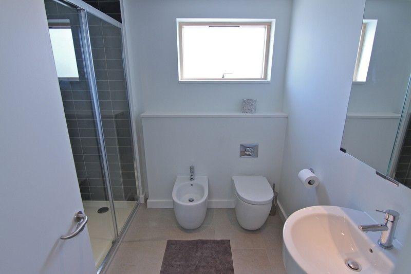 Wall hung 'Roca' wash hand basin and WC with concealed cistern. Porcelain tile floor, chrome radiator towel rail and side facing window with obscured glass.