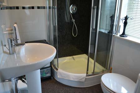 En suite: Three piece shower room in white, comprising of a corner shower cubicle housing a Grohe