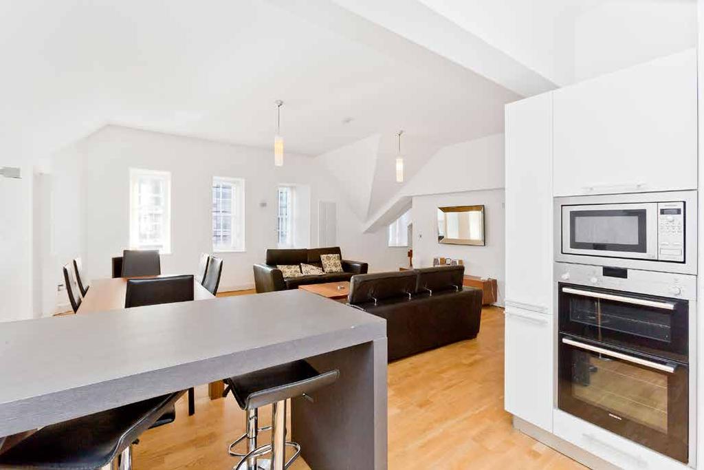 .. Nestled into the corner of this generously-proportioned room is an ultra-modern kitchen, with a breakfast bar casual dining, and featuring an array of sophisticated, simply-styled cabinets,