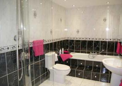 a jacuzzi bath with shower attachment, walk-in shower with curved glass screen, pedestal wash hand