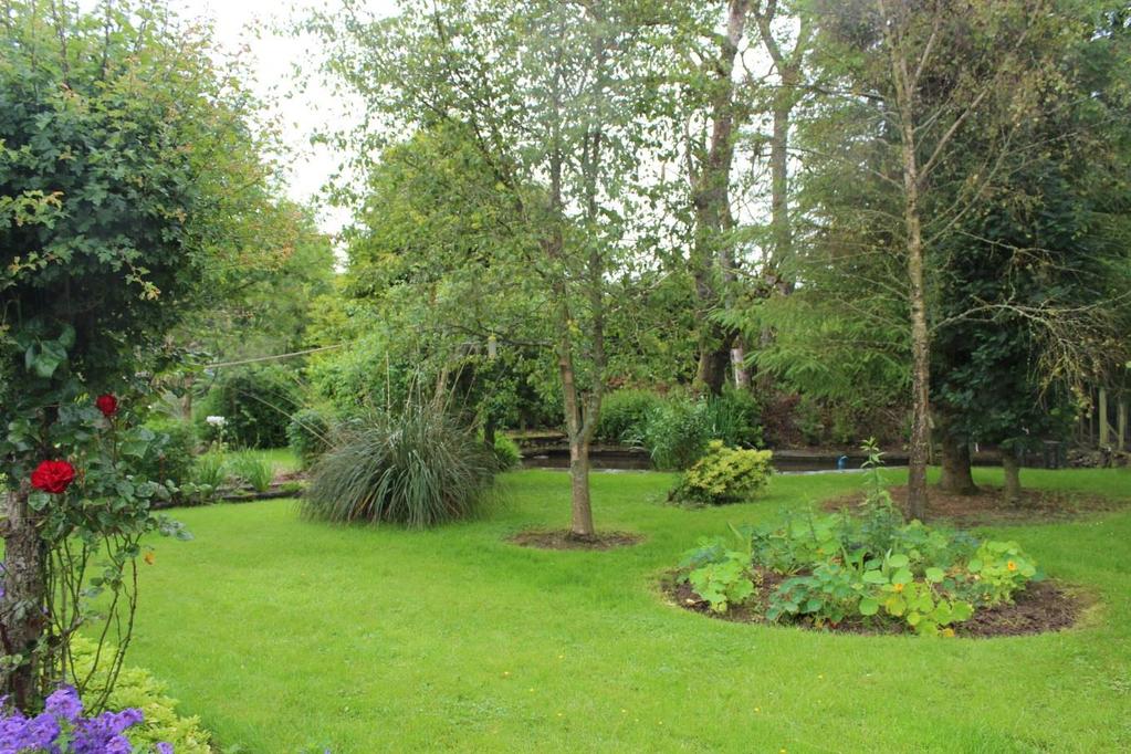 SIDE GARDEN : The large gardens to the side of the property have been attractively landscaped with a large area of lawn bounded by mature well stocked flower and shrub borders and an ornamental pond.