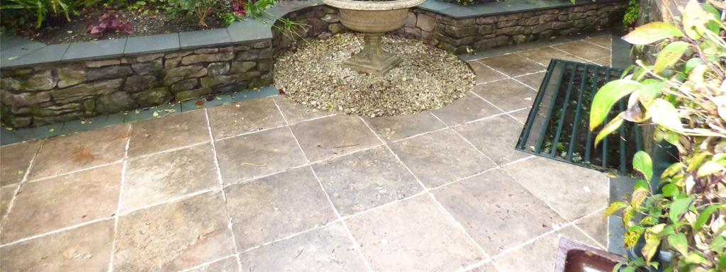 The garden has natural stone tiled flooring with raised flower beds with retaining walls with slate tops.