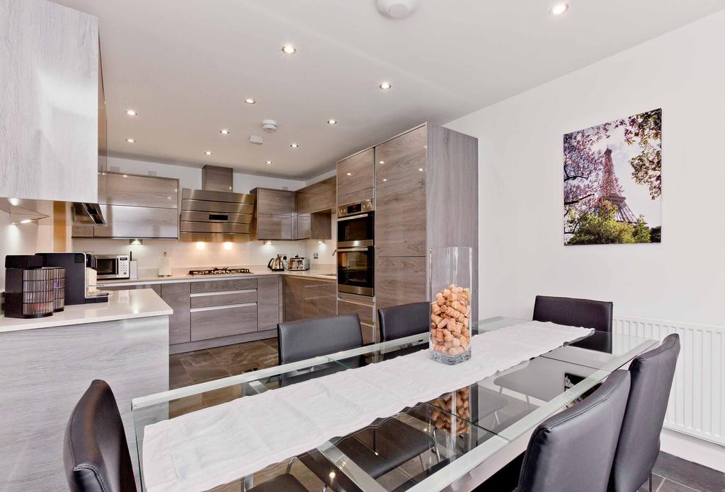 Also bathed in light from a full-height window, the ultra-modern dining kitchen to the front, which is lined with extensive grey-oak effect cabinetry and sparkling white solid work