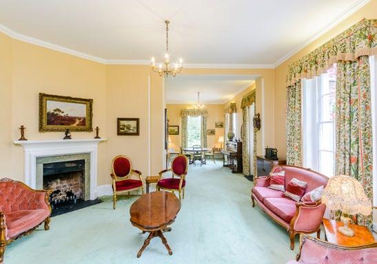 The sitting room overlooks the garden and features a large bay window, an original fireplace, and double doors opening onto the gardens.