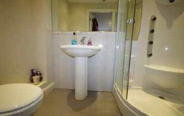 EN SUITE High quality white suite comprising pedestal wash hand basin, low flush WC. Separate curved shower cubicle with body jets. Tiled floor. Heated chrome towel rail.