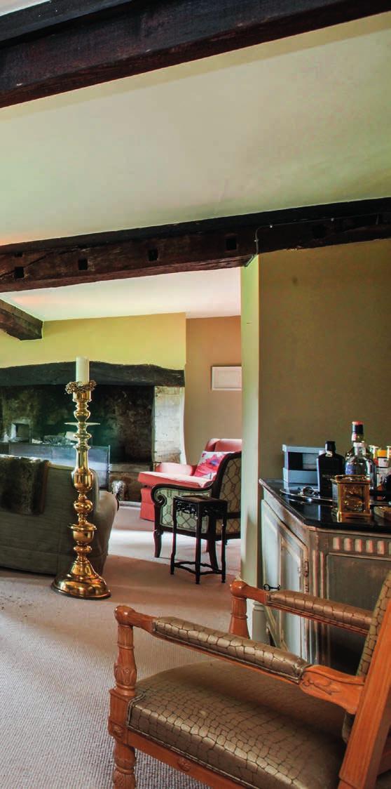 From the entrance porch, a door opens into the dining room, which has a fireplace and carved chequer-board ceiling timbers.
