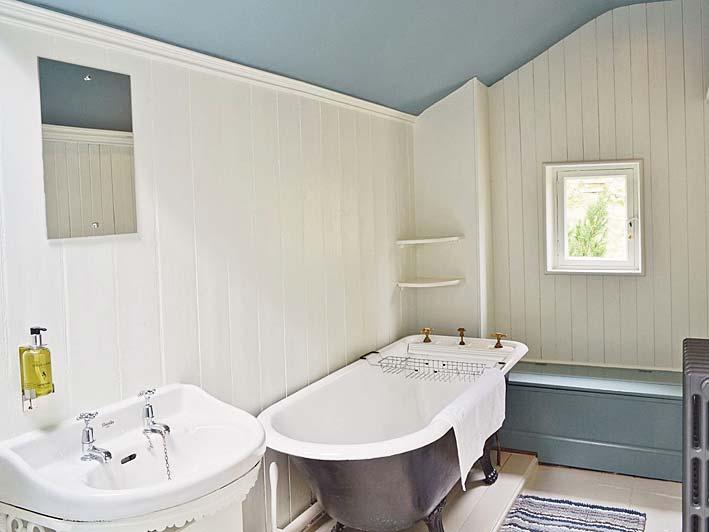 BATHROOM 15 01 x 5 03 Shower cubicle with a quirky, stable style door; roll top bath; toilet; sink; cast iron radiator; Velux window; built in storage box seat; 2 x ceiling downlights.