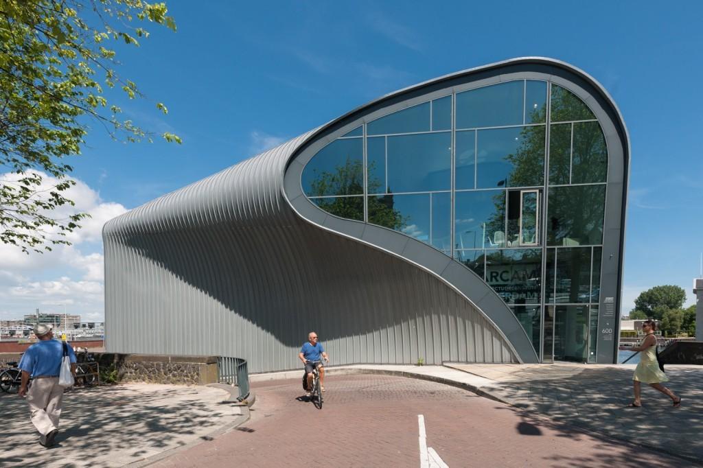 blob-shaped building is clad with coated aluminium strips, folded over the roof On the waterside, the building is cut open to reveal its interior behind a large glass façade photo: Dirk Verwoerd
