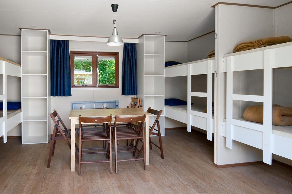 There are four bunk beds, four cupboards and a table with eight chairs.