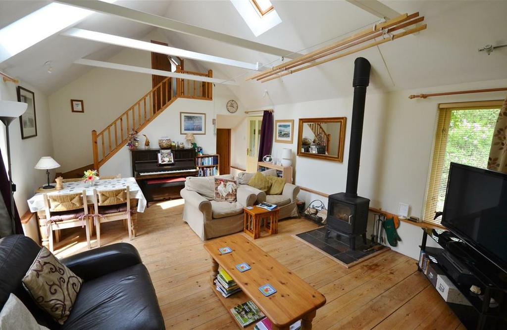 Wooden flooring, high ceiling with exposed beams, Morso multi fuel burner on a tiled hearth, stairs to bedroom two, steps down to