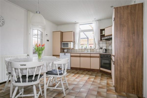 The semi-open kitchen has a tiled floor, part clean masonry and part coarse sanded walls and a wooden