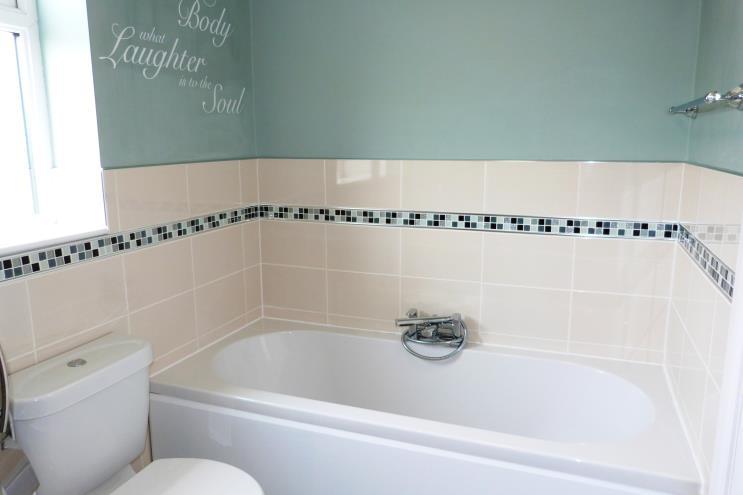 Modern refurbished bathroom comprising panelled bath with central mixer tap, corner shower cubicle