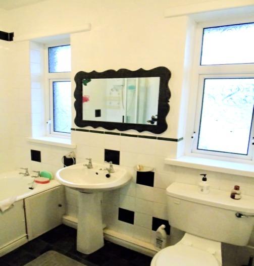 over, low flush WC, pedestal wash hand basin, fully tiled walls.