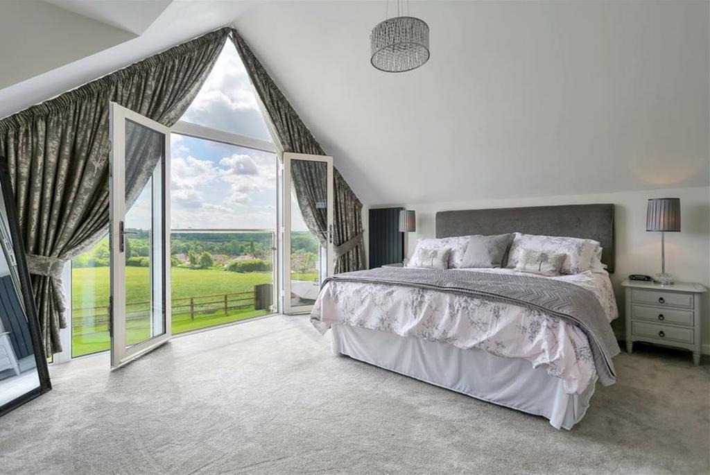 a bedroom with full height gable end windows and French