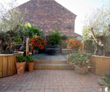 brick block paved patio area with footpaths around, central lawned area with flower borders around and established ferns, trees and shrubs, etc There is an ornamental pond with stone walling around