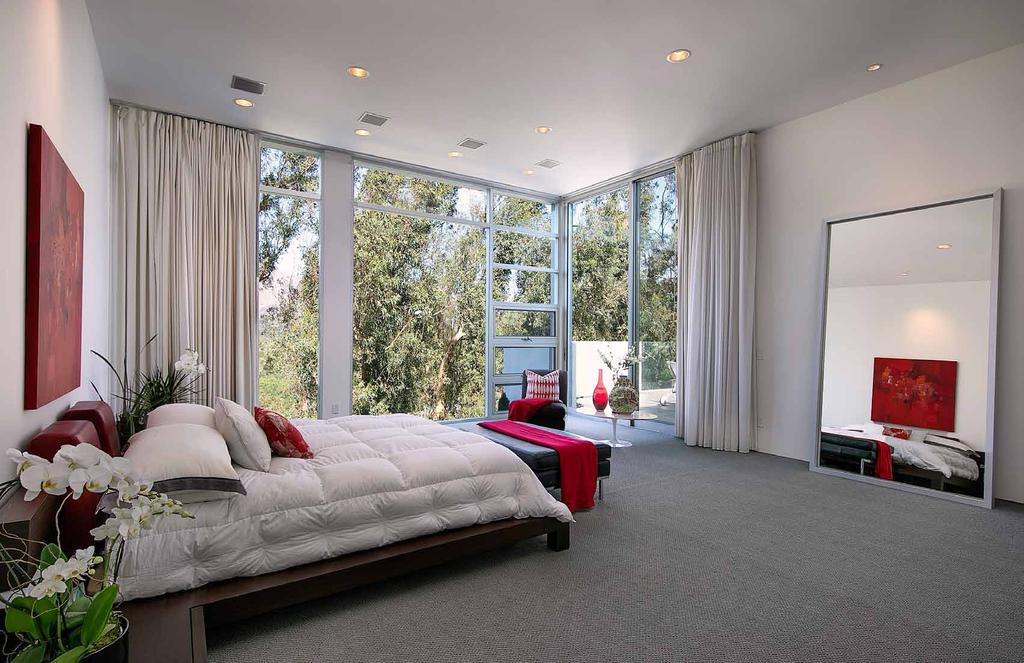 The master bedroom is breathtaking in scale and beauty with its floor-to-ceiling walls of glass and steel framed details that open to impeccable gardens below and mountain views beyond.