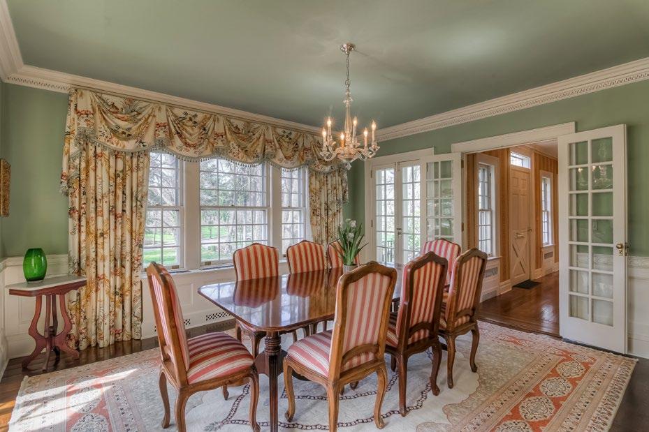 The front-to-back living room with woodburning fireplace is perfect for large-scale formal entertaining and connects to the warmly paneled library with