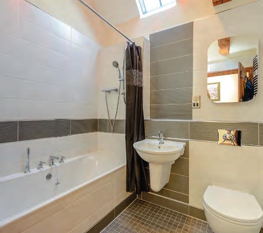 There is a latched door leading to the ensuite shower room with ceramic tiled floor, wash basin, shower cubicle with sliding door and Velux conservation roof window.