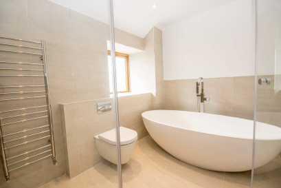 06m (9'5" x 6'9") Luxury white suite with an Ashton & Bentley shaped oval freestanding bath with chrome pillar tap and shower head, separate walk-in shower with