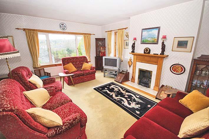 The spacious sitting room has a flame effect gas fire set over polished stone hearth with wooden mantel over. Radiator with thermostatic control and wall lights. There is an alcove to one corner.