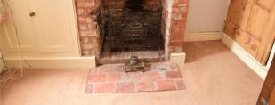 brick hearth, useful understairs storage cupboard, door providing access to the stairs rising to the first floor landing,