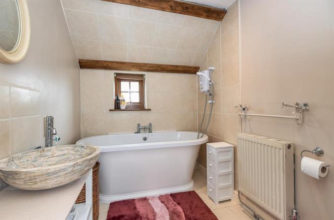 under, a close coupled WC, radiator, extractor fan, tiled flooring, tiled splashbacks to the sink and around the bath, wooden beams, loft access, frosted upvc double glazed window to the side.