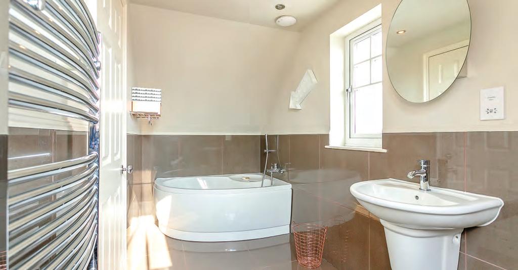 leads to the ensuite bathroom which is again fitted with modern contemporary tiling, corner bath with shower attachment,