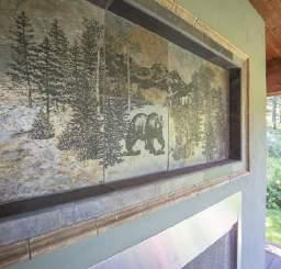 The covered deck features a wood-burning fireplace with slate tile and decorated by a mosaic of a