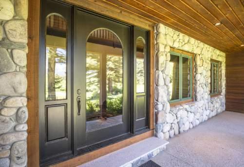 The rich redwood lap-siding exterior is accented by sage-forest green trim as well as river rock stone at the front and side door s covered porches.